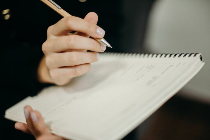 Une main prend des notes au stylo dans un carnet
